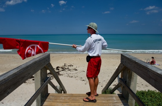 VERO BEACH - Nathan Rieck, lifeguard supervisor with the City of Vero Beach, takes down the double-red flag while closing down the Humiston Park lifeguard stand for the day on Wednesday afternoon. The flags, which signify the beach is closed to swimming, were flying due to a shark attack.